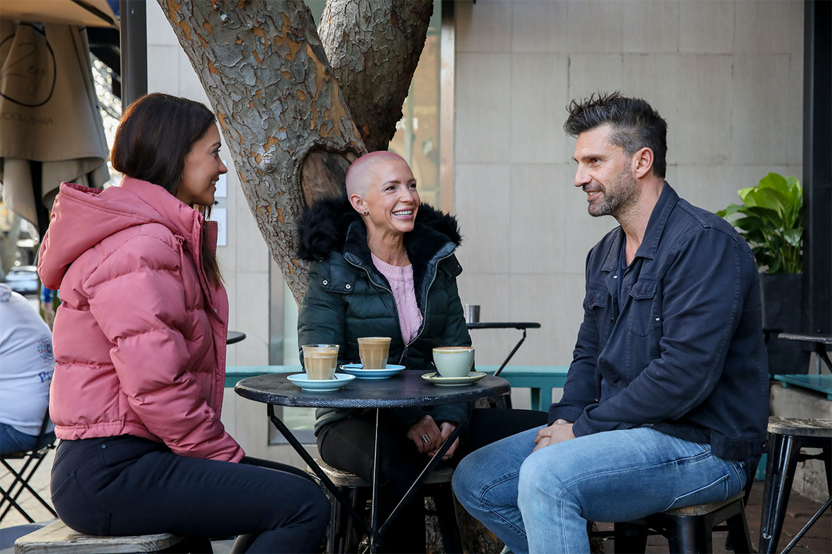 Three people having a coffee at outdoor café in city