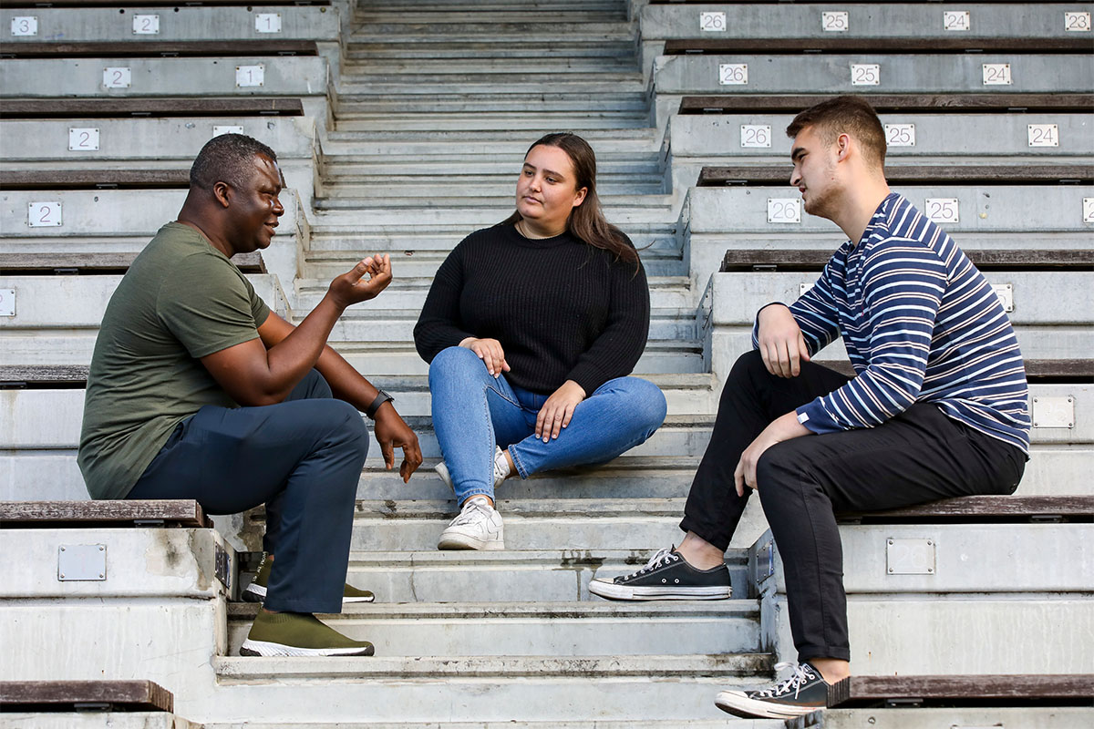 Three people talking sitting on step outside